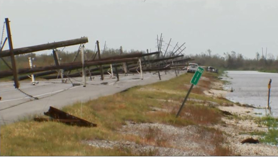 A road blocked by downed utility poles and power lines