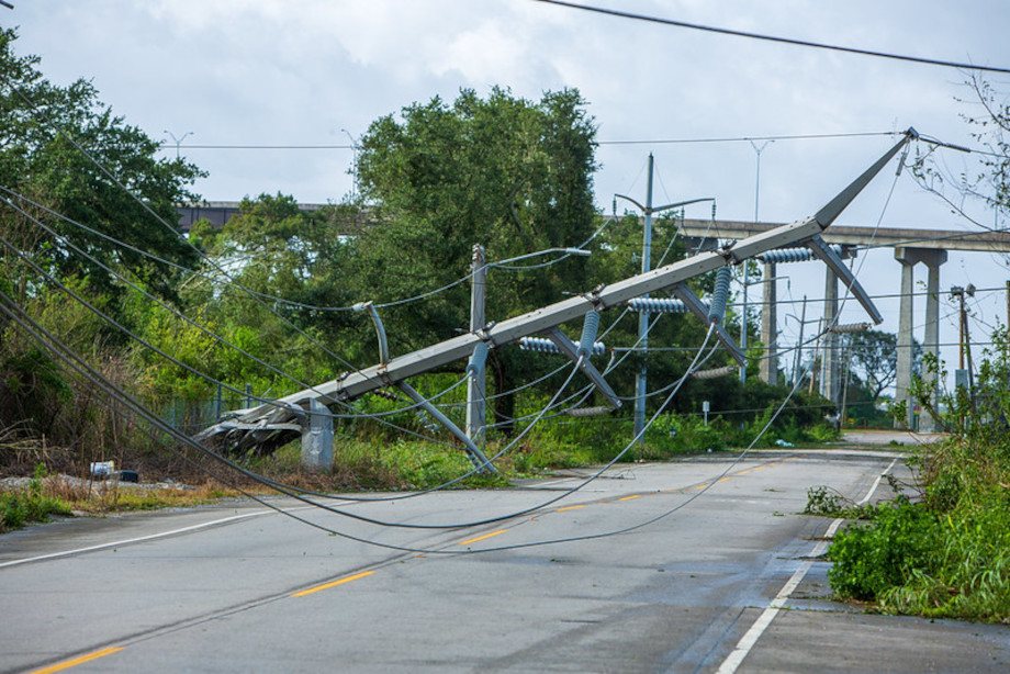 A twisted transmission tower lies over a road amid cables. Entergy Photo