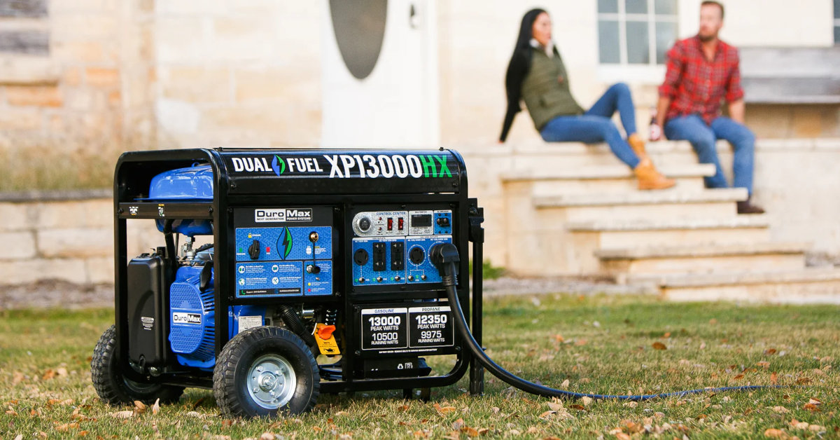 A young couple sits on their backyard porch with a DuroMax XP13000HX Generator in the yard.